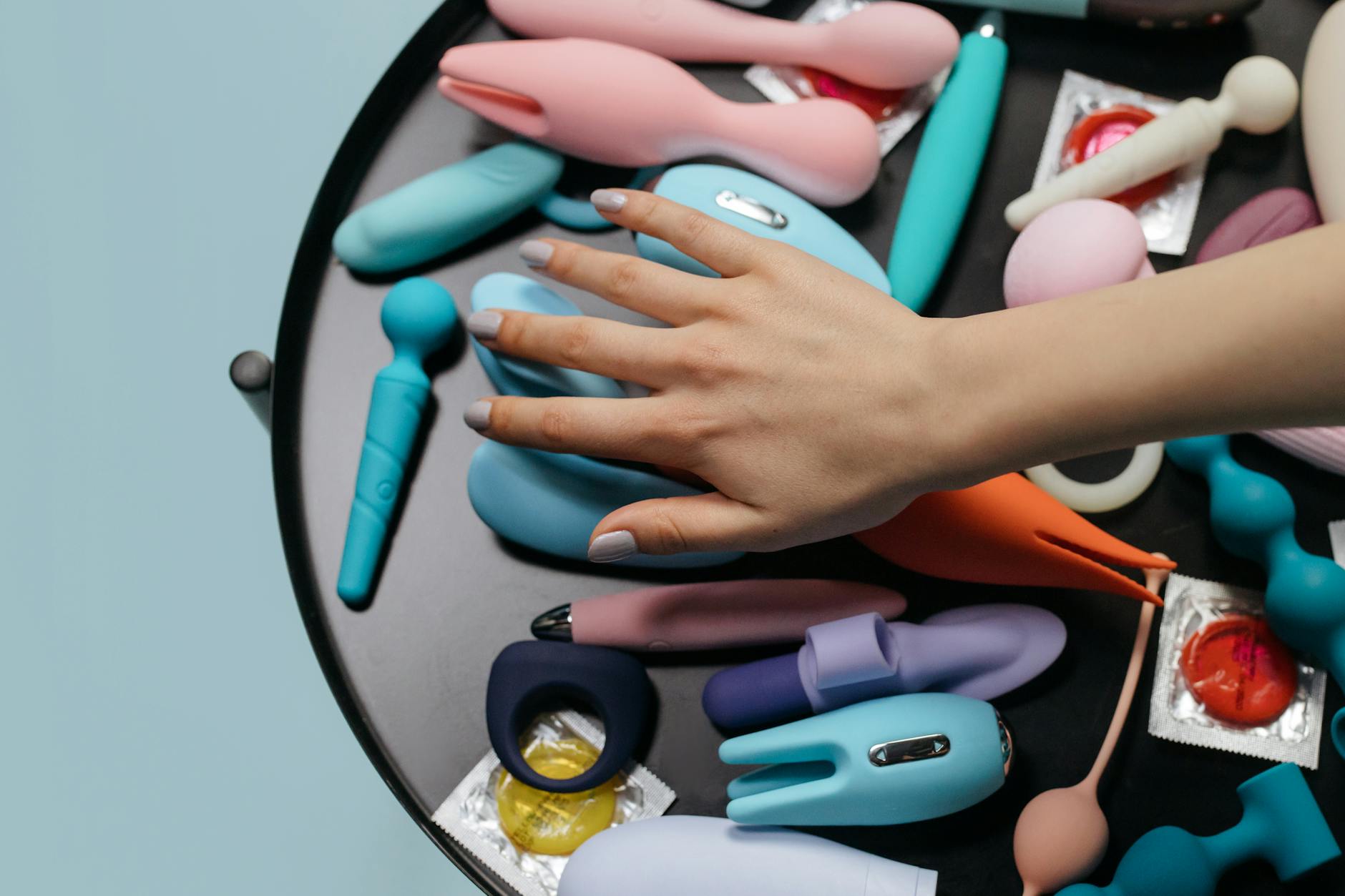 A hand holding an orange vibrator against a purple backdrop, showcasing modern design for enhanced sensation.