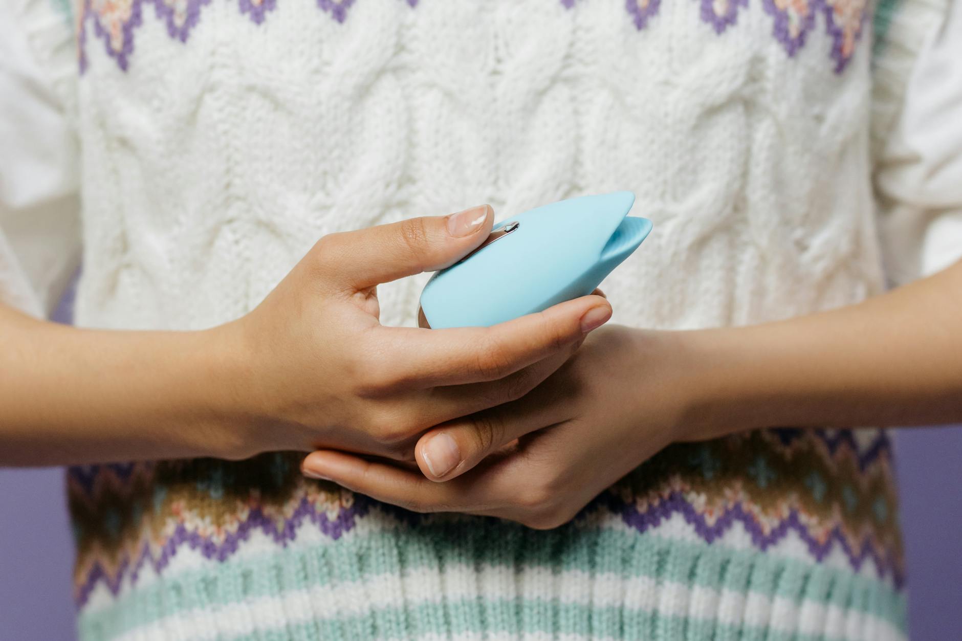 A blue silicone sex toy held in hand against a solid purple background, promoting self-love and sexuality